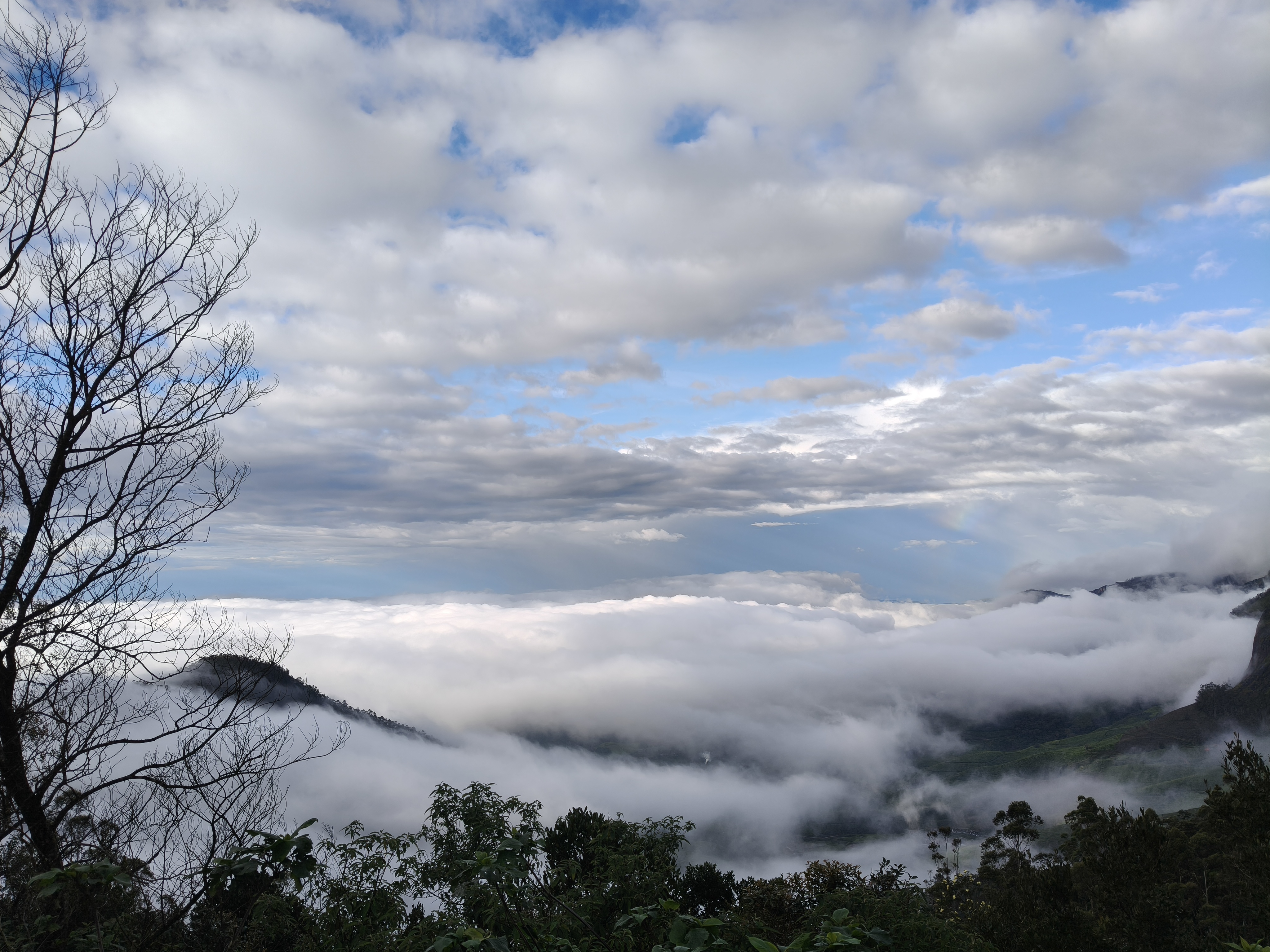 Kolukkumalai mountain peak with clouds drifting over steep rocky cliffs